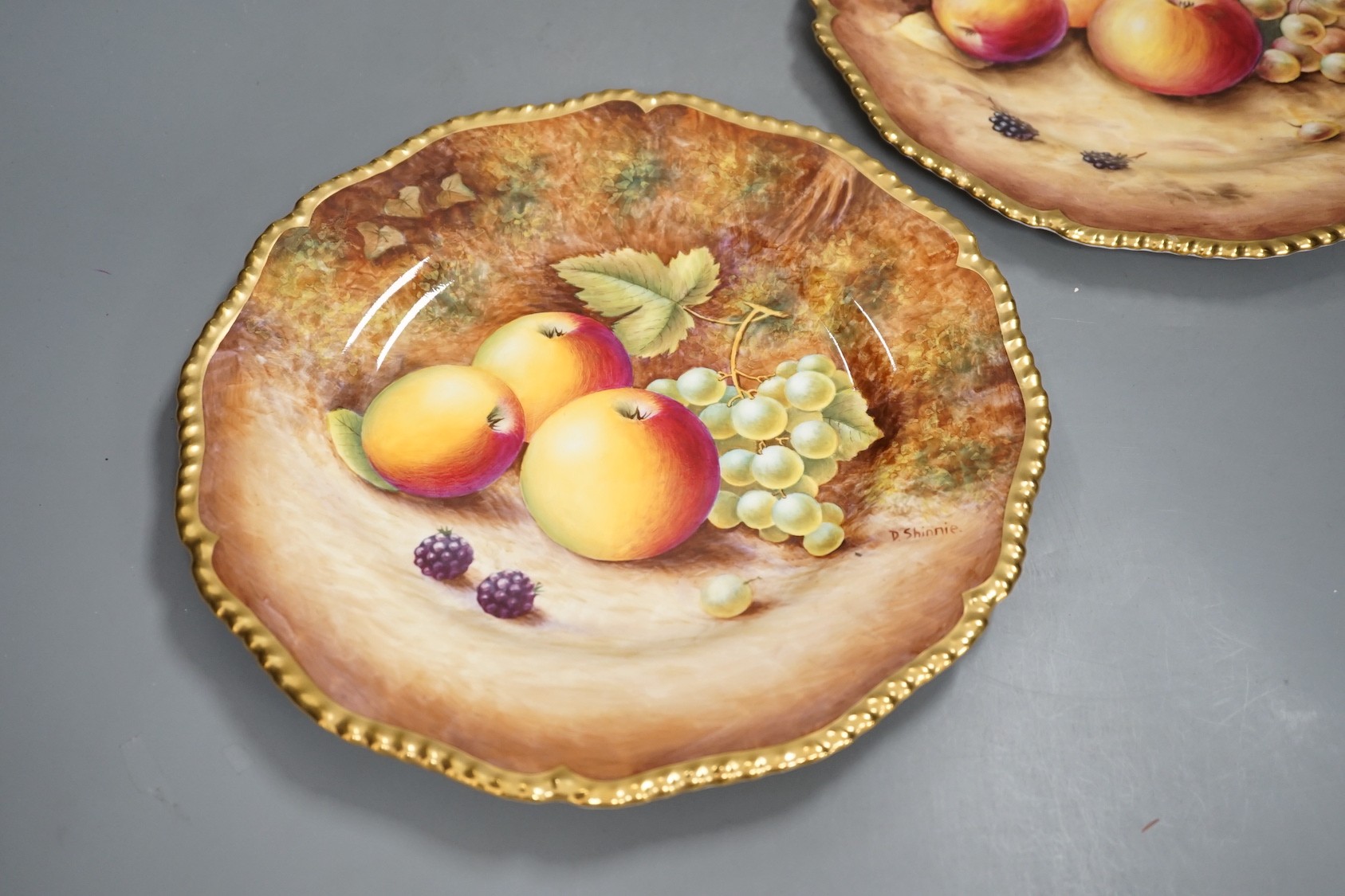 A pair of Royal Worcester fruit painted dinner plates, post war, by D. Shinnie and T. Nutt, 27cm diameter